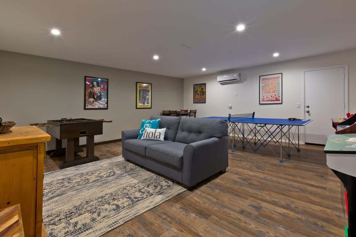 A living room with a gray sofa, a blue table, and a pool table.