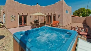 A hot tub in front of a stucco building with a patio area, outdoor furniture, and a satellite dish. - Hacienda Getaway Pool, Hot Tub, & Steps to trails. (La Quinta)
