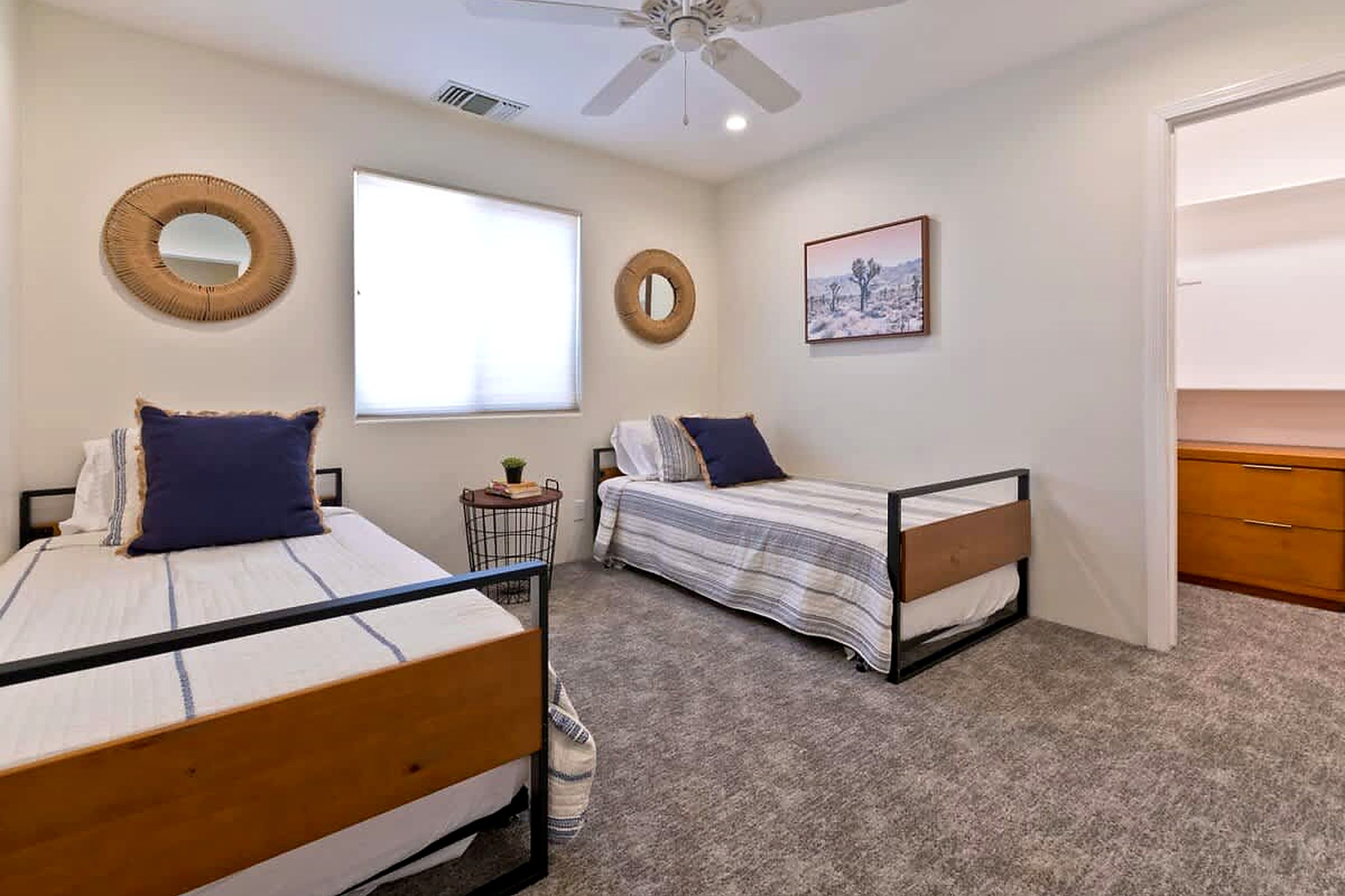 Een slaapkamer met twee bedden, een plafondventilator, een raam en een deur.