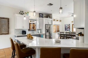 Una cocina moderna con armarios blancos, una isla central e iluminación colgante.