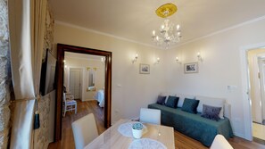 Ein gemütliches Wohnzimmer mit einem grünen Sofa, einem Holzesstisch mit weißer Dekoration und einer Kristallleuchter.