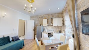 A compact living space with a kitchenette, a dining area, and a sofa. - Chrysanta Apartments (Split)