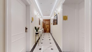 A hallway with white walls, a marble floor, and a wooden door at the end. - Chrysanta Apartments (Split)