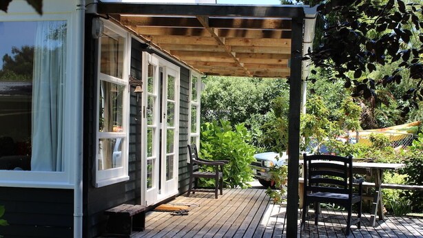 A wooden deck with a covered seating area, a table, and chairs. - Summer and winter retreat
3 bedrooms - 2 bathrooms (Hatepe)