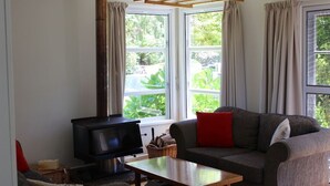A living room with a sofa, a table, a television, and a window with curtains. - Summer and winter retreat
3 bedrooms - 2 bathrooms (Hatepe)