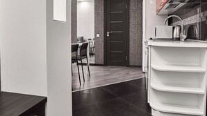 Una cocina moderna con encimera blanca, baldosas oscuras y una pared de acento roja.