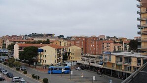 Un paisaje urbano con edificios de varios pisos, un autobús azul y coches estacionados en la calle.