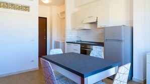 A modern kitchen with white cabinets, a stainless steel refrigerator, and a dining table with chairs. - Appartamento Al Centro della Vacanza (Portoferraio)