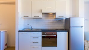 A compact kitchen with white cabinets, a built-in oven, and a stainless steel refrigerator. - Appartamento Al Centro della Vacanza (Portoferraio)