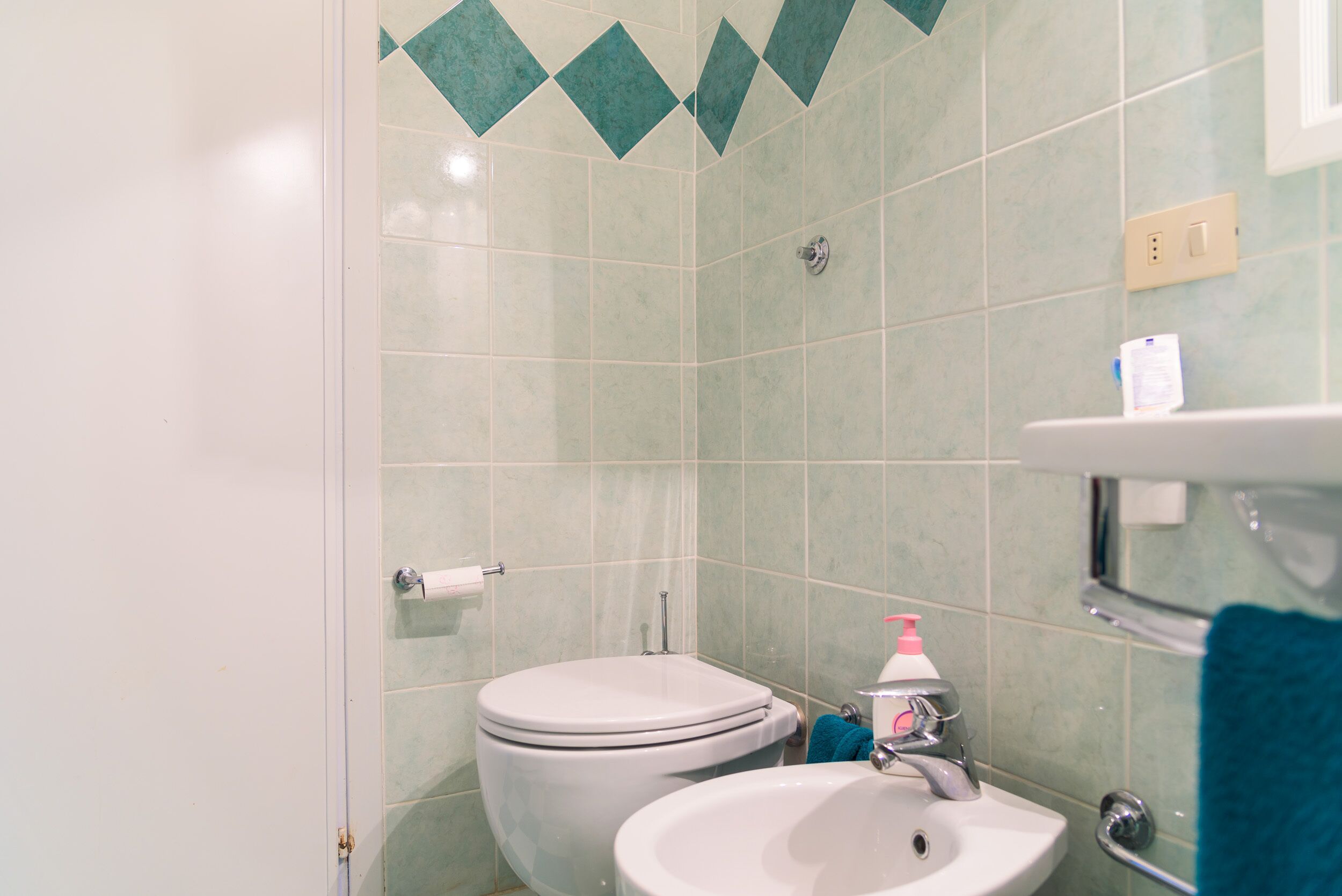 A bathroom with a toilet, sink, and a towel rack.