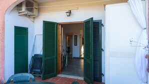 An open doorway leading to a room with a tiled floor, a chair, and a table. - Appartamento Il Mare in Cartolina (Portoferraio)