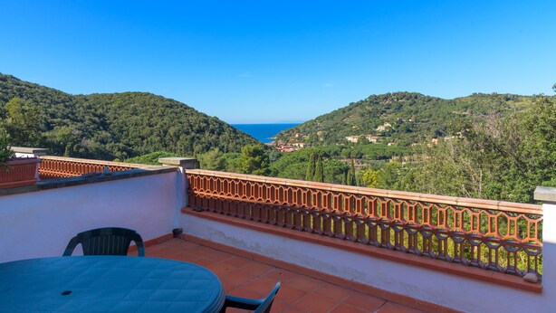 A terrace with a table and chairs, overlooking a valley with a view of the sea and hills. - Appartamento Il Mare in Cartolina (Portoferraio)