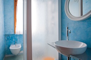 A bathroom with a white sink, a mirror, and a window with a curtain.