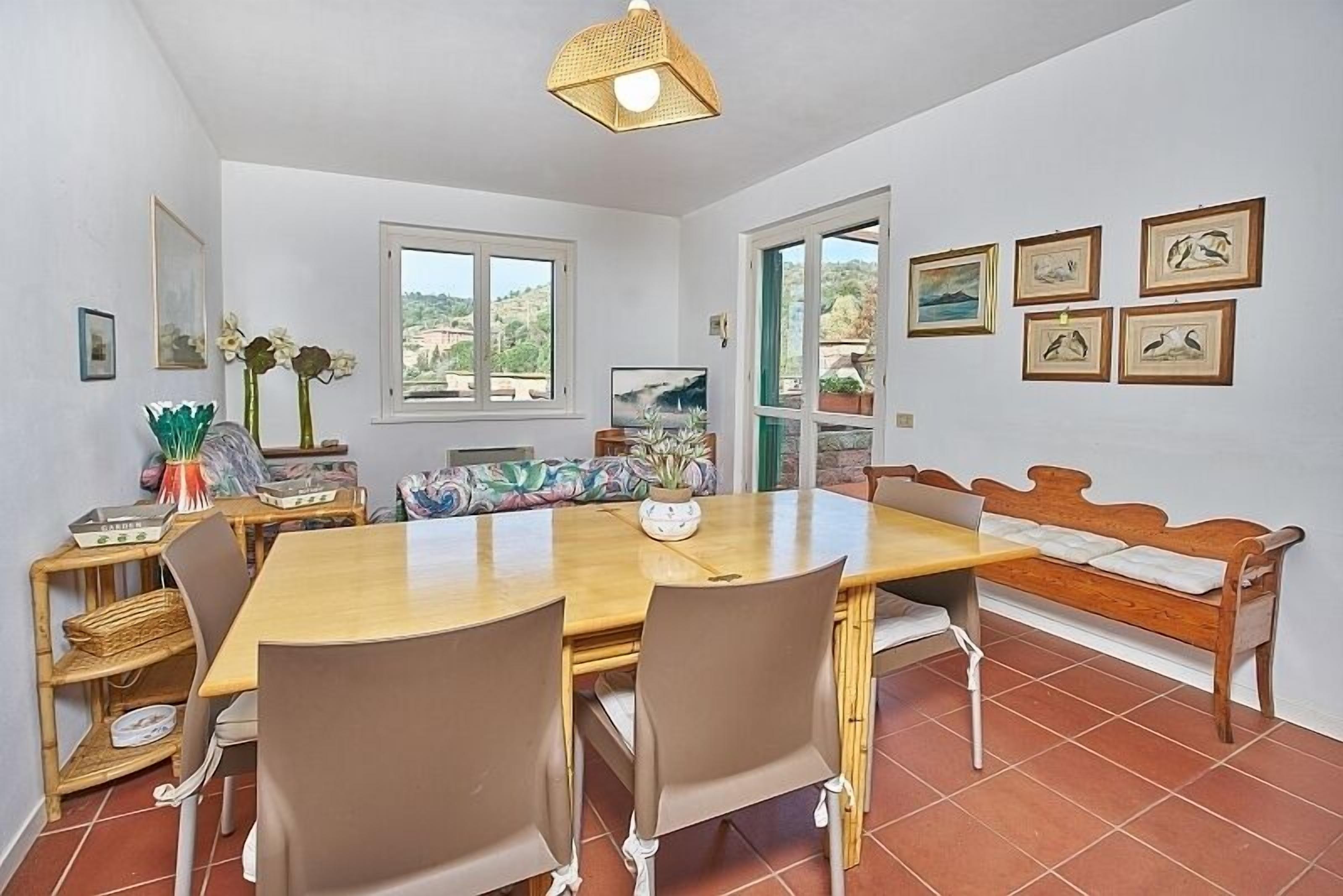 A dining area with a wooden table, chairs, a bench, and a view of the outdoors.