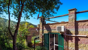 A rustic stone building with a green door, a satellite dish, and a brick chimney. - Appartamento Via dei Lecci (Rio)
