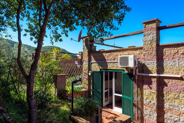 A rustic stone building with a green door, a satellite dish, and a brick chimney.