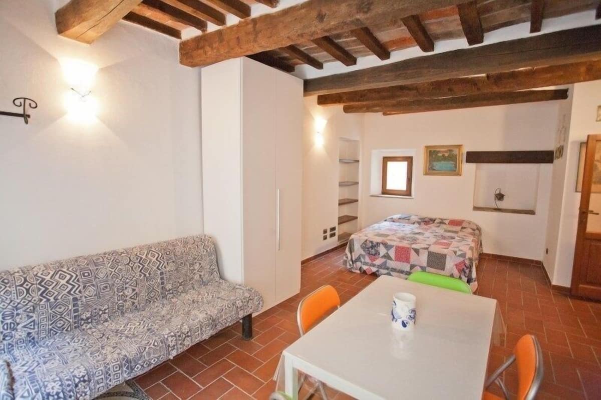 Ein gemütliches Zimmer mit einer gemusterten Couch, einem kleinen Tisch mit einer Tasse und einem Bett mit einer Steppdecke.