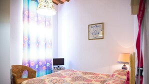 Un dormitorio con una cama, una silla, un escritorio con computadora y una lámpara.
