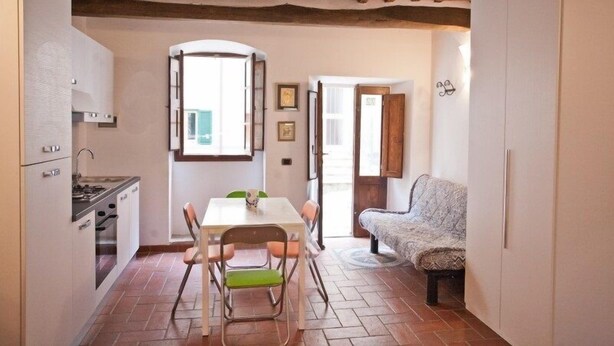 Cocina compacta con mesa y sillas, un sofá y vistas a través de una puerta abierta.