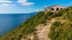 Una casa costera con una escalera de piedra que lleva a un edificio blanco con techo rojo, con vistas al mar.