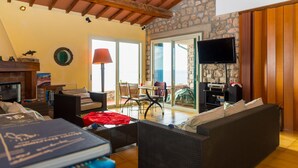 Una sala de estar acogedora con chimenea, asientos cómodos, televisión y una pared de piedra.