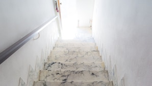 Eine Marmortreppe führt zu einem hellen Raum mit weißen Wänden.