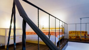 A bedroom with a bed, a wooden floor, a railing, and a window. - Appartamenti Il Grigolo (Portoferraio)