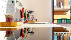 A kitchen with a glass container of grains, a wooden cutting board, and a stainless steel sink. - Appartamenti Il Grigolo (Portoferraio)