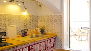 Una cucina con un piano di lavoro giallo, un lavello e una finestra che si affaccia su un balcone con sedie.