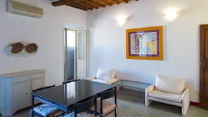 Una stanza con soffitto in legno, un tavolo da pranzo con sedie, un divano e un condizionatore d'aria a parete.