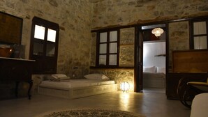 Una habitación con paredes de piedra, una cama, un escritorio y una silla.