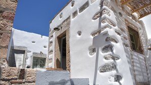 Un edificio con fachada blanca que presenta detalles de piedra y una pérgola de madera.