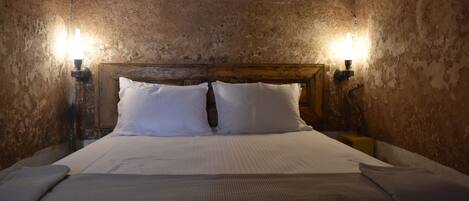 A bed with white linens, two bedside lamps, and a wooden headboard in a room with textured walls.