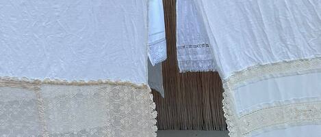 A tent-like structure with a lace border, a wooden floor, and a vertical striped wall in the background.