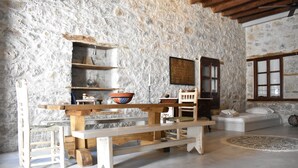 Interior rústico de pared de piedra con un banco de madera, una pequeña mesa y un sofá.