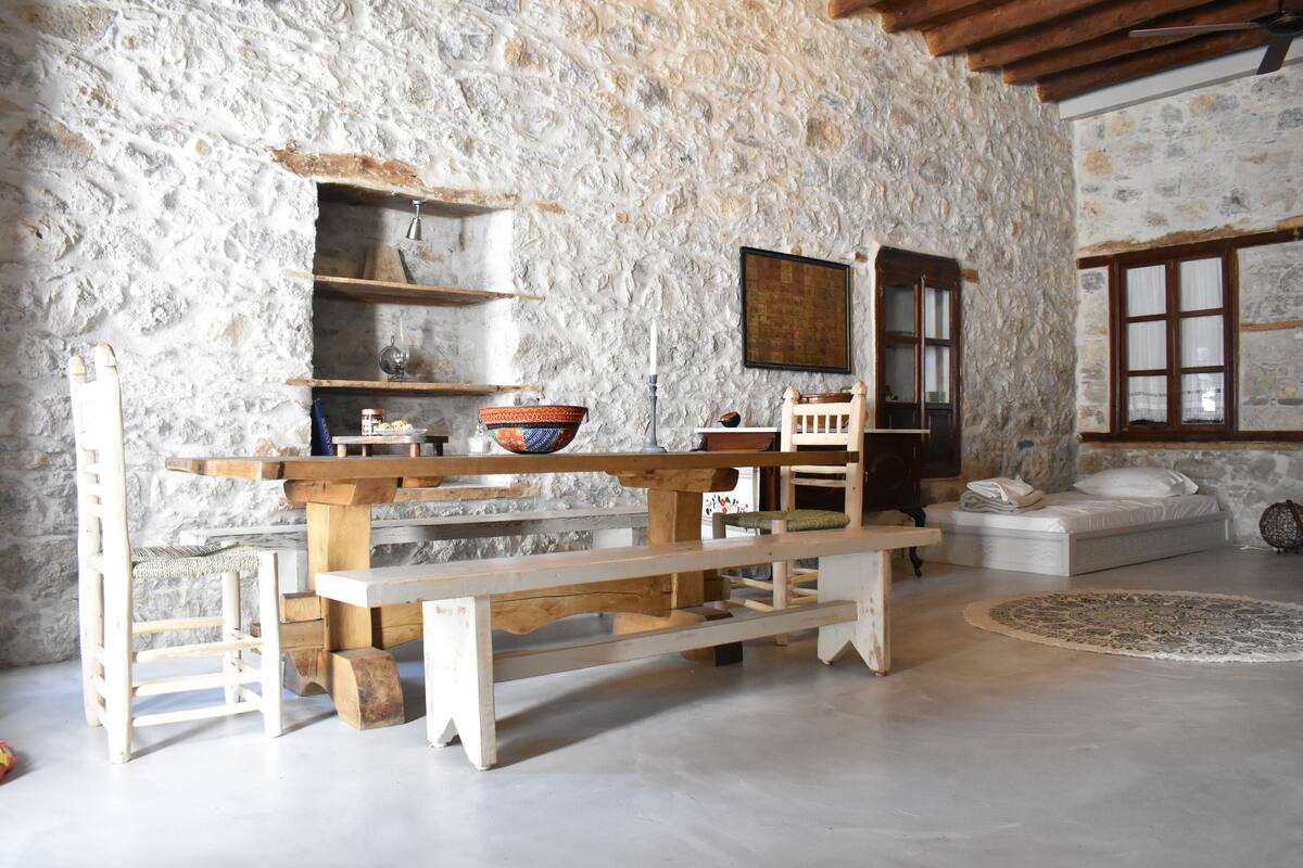 A rustic stone wall interior with a wooden bench, a small table, and a sofa.