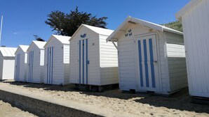 Fila de cabanes de platja blanques amb ratlles blaves, numerades de 17 a 22, sobre sorra.