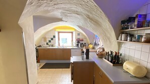 A kitchen with an arched ceiling, a central island, and a patterned rug. - Holiday suite "Chalet" in the "Ferienhaus Burgcafé" (Betzenstein)