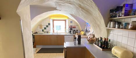 A kitchen with an arched ceiling, a central island, and a patterned rug.