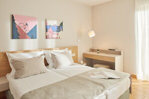 A hotel room with a bed, a desk, and two wall art pieces.