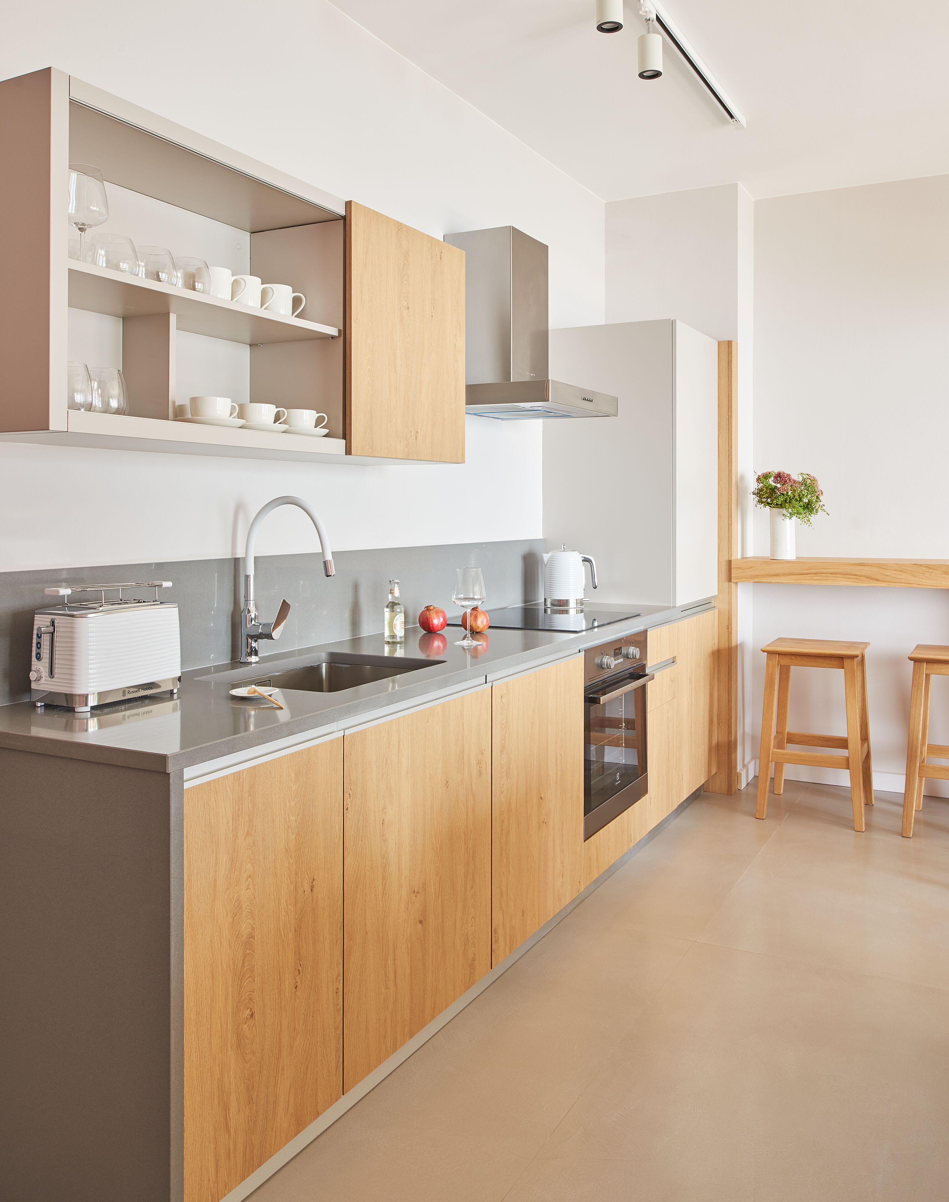 A modern kitchen with wooden cabinets, a stainless steel range hood, and a built-in oven.