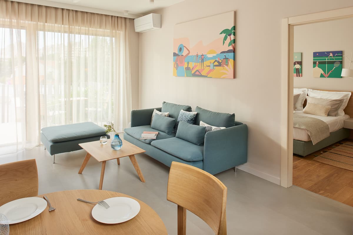 A modern living room with a sofa, a coffee table, and a dining area with a table set for two.