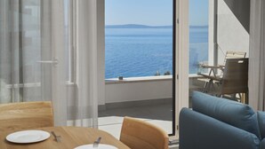 A balcony with a view of the sea, a dining table with plates and cutlery, and a blue sofa. - Eol Apartments Split (Split)