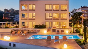 A modern building with a rooftop pool, multiple balconies, and a well-lit exterior. - Eol Apartments Split (Split)