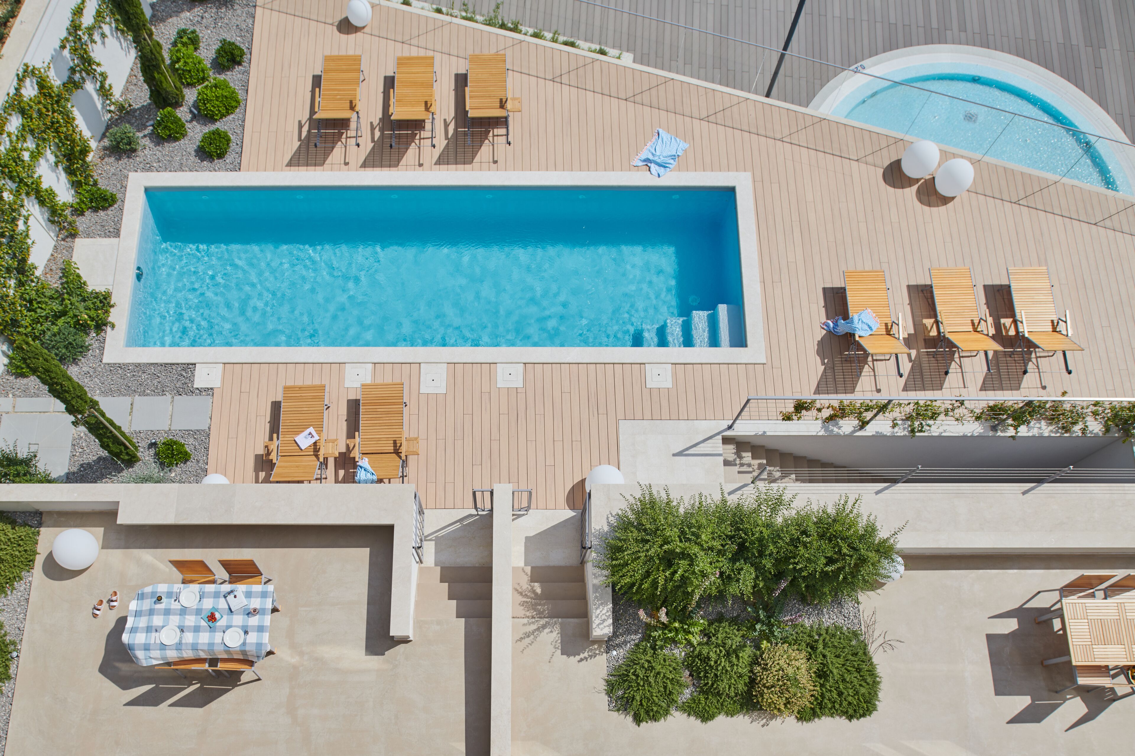 Ein Pool auf dem Dach mit Holzliegen und einem karierten Tisch.