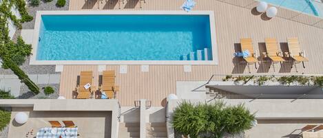 Ein Pool auf dem Dach mit Holzliegen und einem karierten Tisch.