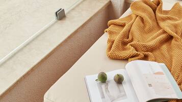 A reading nook with a cushioned bench, a book, and a blanket.