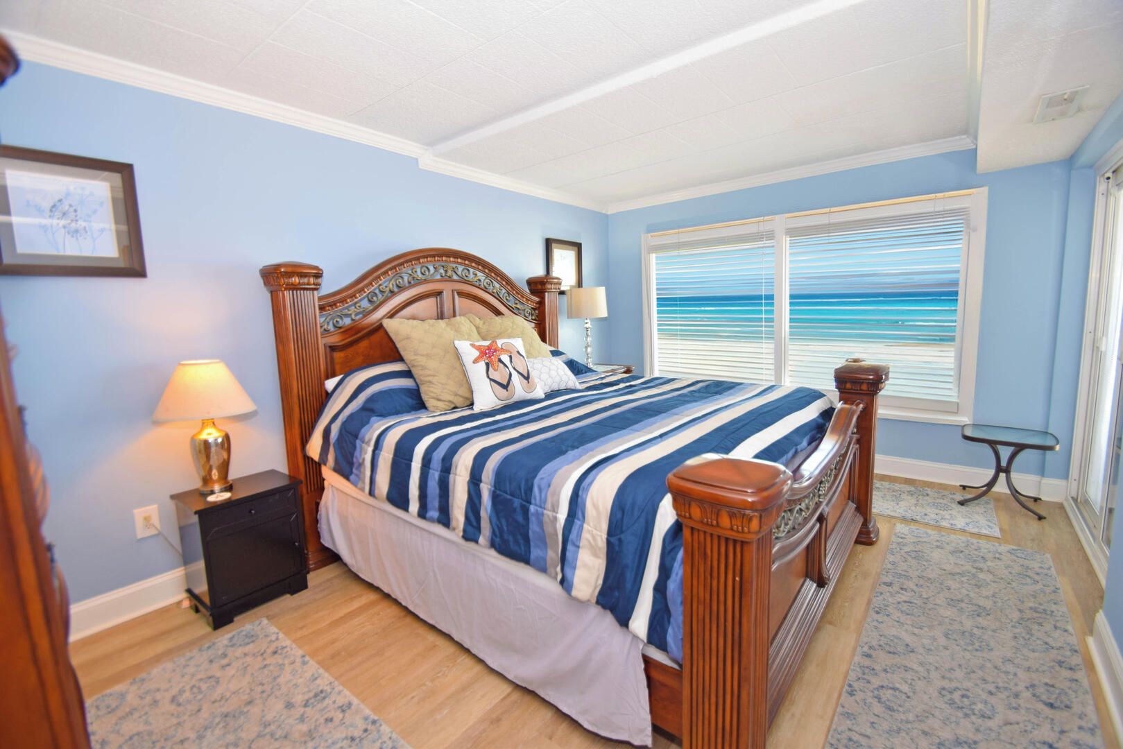 A bedroom with a bed, bedside lamps, a window with a view, and a small table.