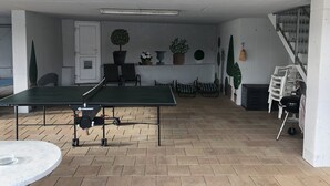 A room with a ping pong table, chairs, a small table, and potted plants. - FeWo Schloß Ramspau - Forsthaus Ostwohnung (5-star DTV) (Ramspau)