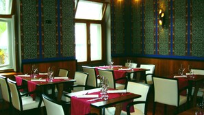 Interior de restaurante con mesas dispuestas para comer, con papel tapiz estampado y paneles de madera.